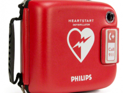 Автоматический наружный дефибриллятор Philips HeartStart в красном защитном футляре на белом фоне