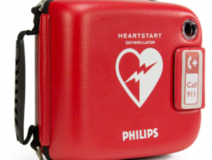 Автоматический наружный дефибриллятор Philips HeartStart в красном защитном футляре на белом фоне